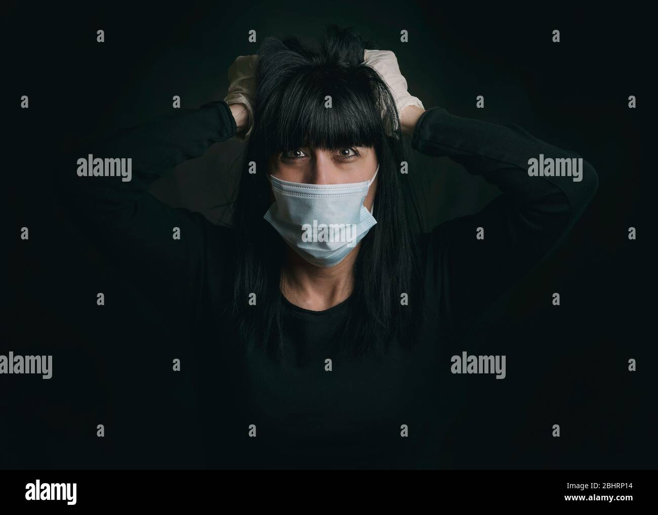Coronavirus, jeune femme portant un masque médical désespérée pour la quarantaine sur fond noir Banque D'Images