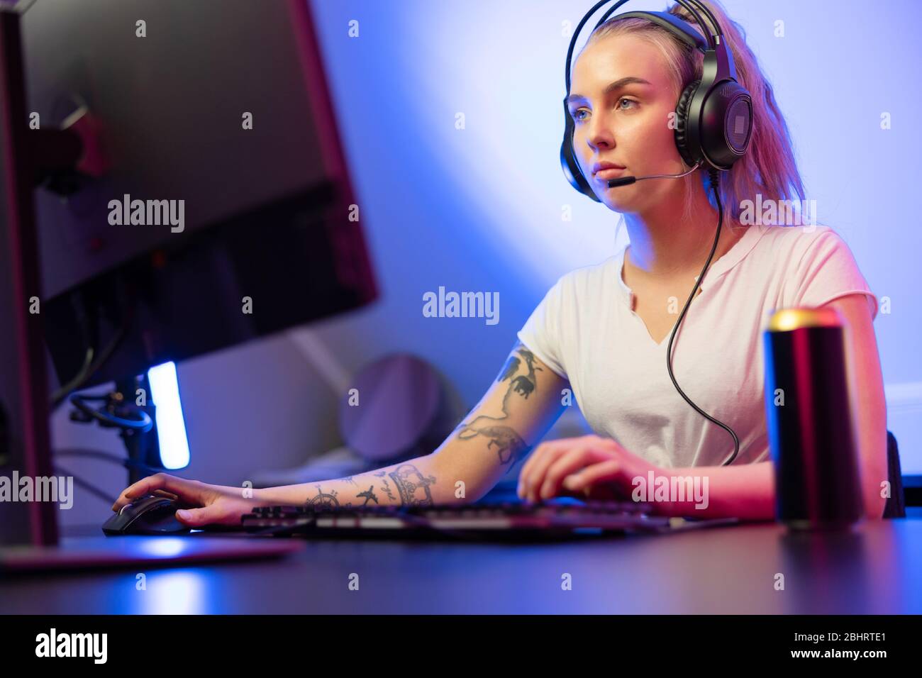 Une fille gamer professionnelle avec casque joue en ligne multijoueur jeu vidéo sur PC Banque D'Images