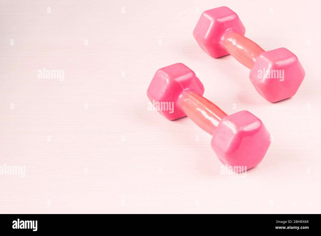 Image rapprochée de deux haltères roses isolées sur fond de bois blanc Banque D'Images
