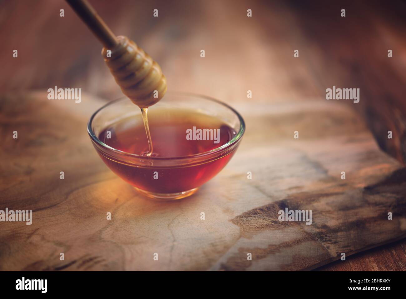 Vue de dessus du miel s'écoutant du balancier miel dans un bol en verre. Gros plan. Nourriture saine bio. Miel épais trempant à partir de la cuillère à miel en bois, à proximité Banque D'Images