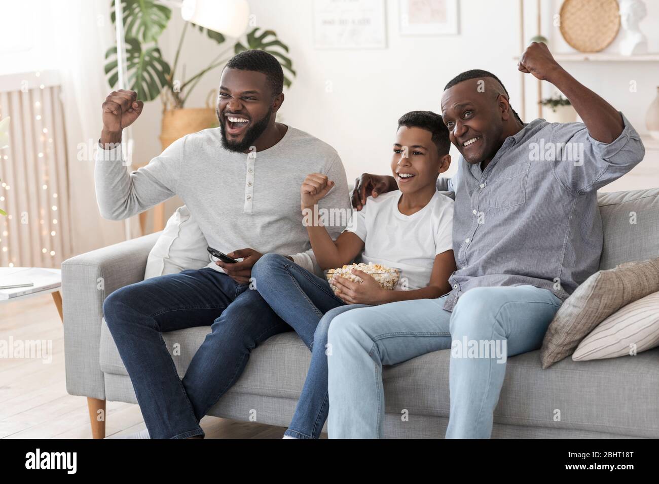 Joyeuse famille noire, père, grand-père et fils regardant le match de football à la télévision Banque D'Images