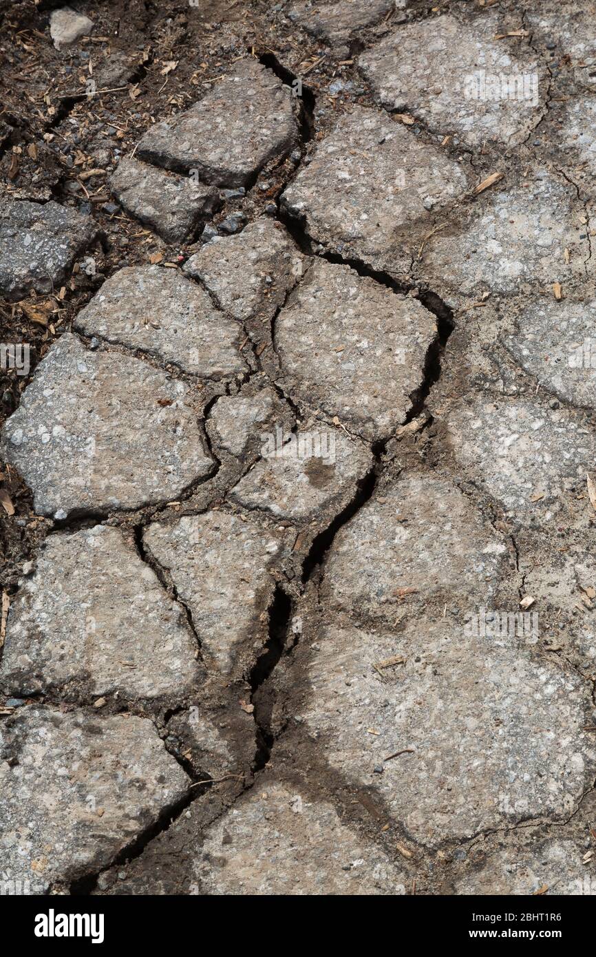 Gros plan sur la surface endommagée et fissurée de la route d'asphalte Banque D'Images