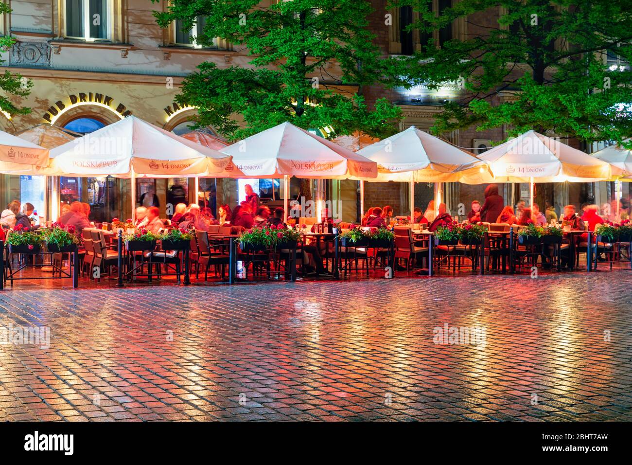 Soirée de pluie avec des personnes assises sur les terrasses de la place du marché de Cracovie Banque D'Images