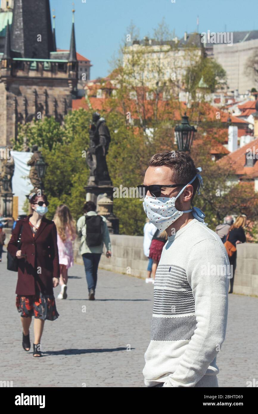 Prague, République tchèque - 23 avril 2020: Les personnes portant des masques médicaux sur le pont Charles. Vieille ville en arrière-plan. Centre-ville en cas de pandémie de coronavirus. COVID-19 crise. Mise au point sélective. Banque D'Images