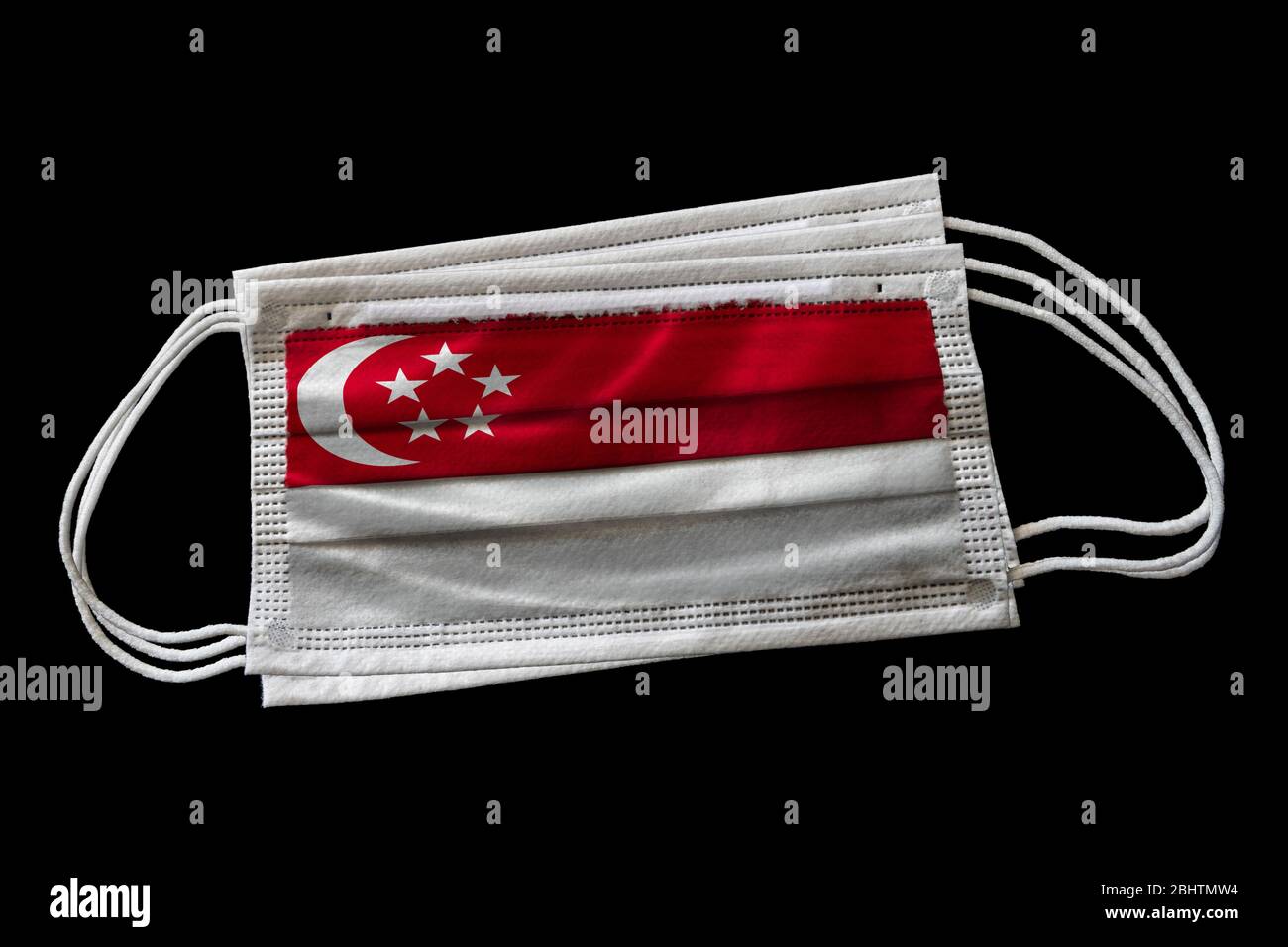 Masques chirurgicaux avec drapeau de Singapour imprimé. Isolé sur fond noir. Concept d'utilisation de masque de visage dans l'effort singapourien pour combattre Covid-19 cor Banque D'Images