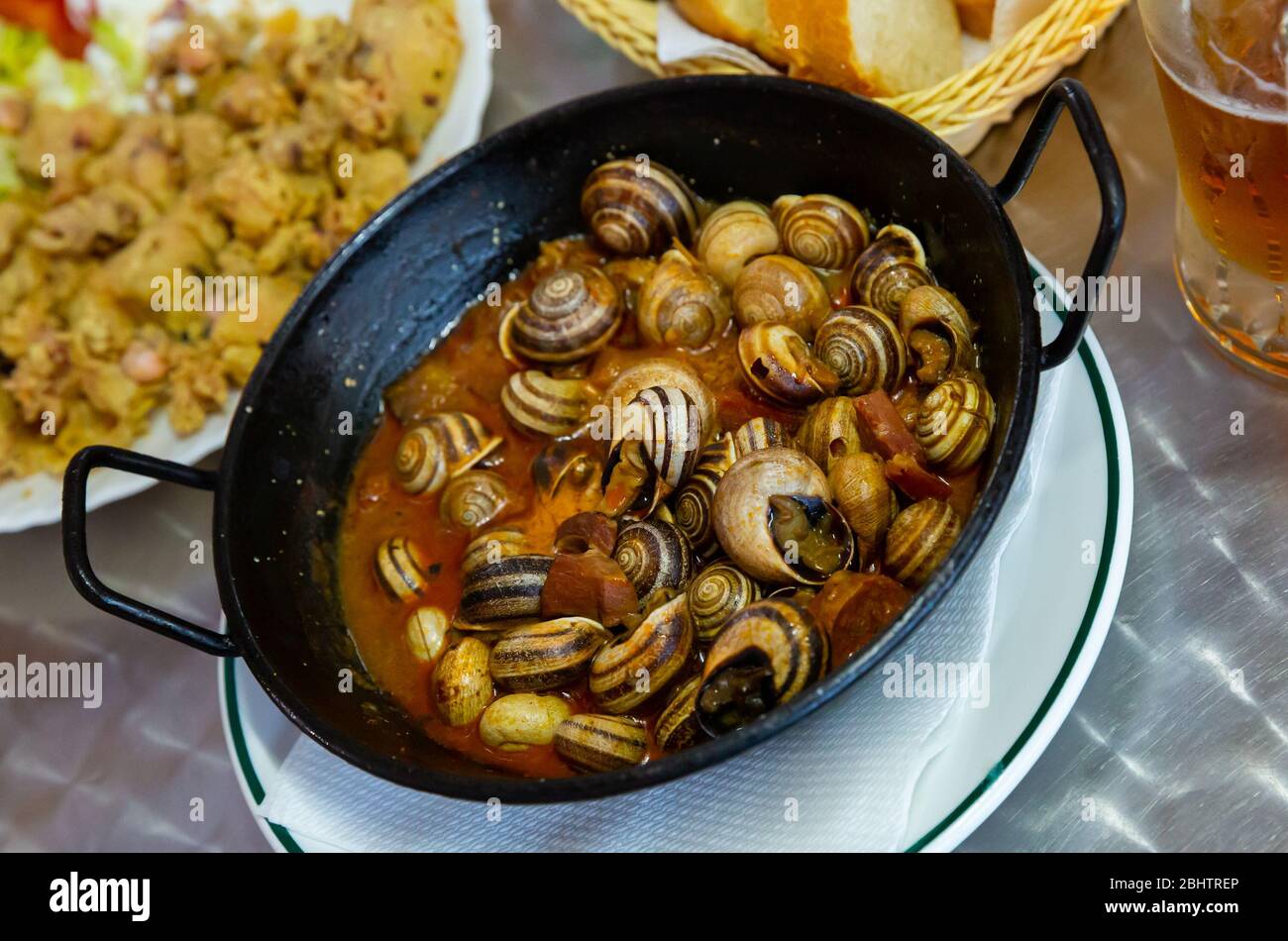 Tapas populaires espagnoles - escargots de style maison (caracoles) compotés avec des saucisses chorizo dans la sauce Banque D'Images