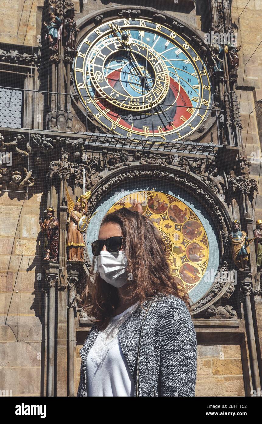 Jeune femme caucasienne avec lunettes de soleil et masque médical photographié devant l'horloge astronomique Orloj à Prague, en République tchèque. Voyager, tourisme pendant coronavirus. Concept COVID-19. Banque D'Images