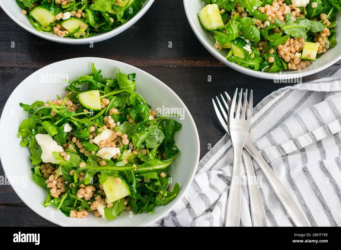Salade de limonie à l'Arugula avec couscous, concombres et feta : salade d'arugula avec morceaux de concombre, morceaux de fromage feta et couscous de perle de blé entier Banque D'Images