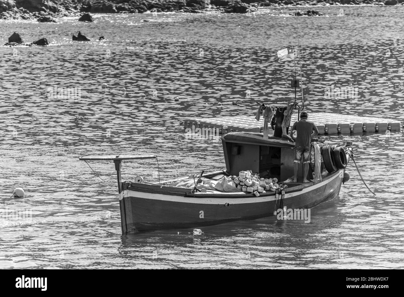 Bateau de pêche ancré dans la plage après une journée de travail de pêche dans l'océan Pacifique. Un bateau bleu avec drapeau chilien et équipement de pêche sur l'eau calme Banque D'Images