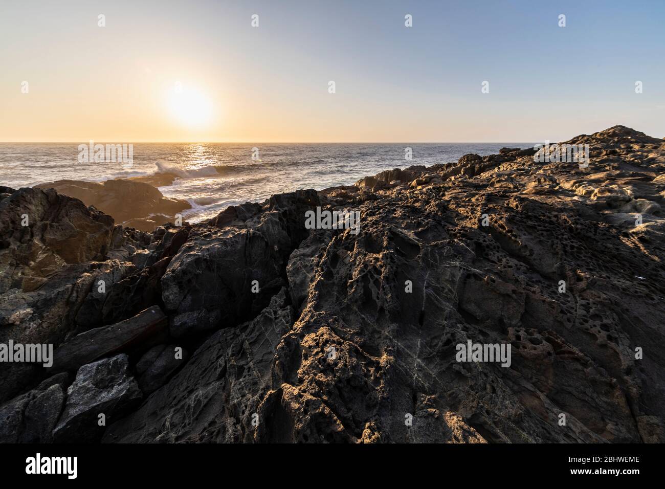 Une vue imprenable sur le coucher du soleil sur l'eau sur la côte chilienne. Un paysage idyllique de plage avec la lumière du soleil illuminant les rochers avec des tons orange Banque D'Images