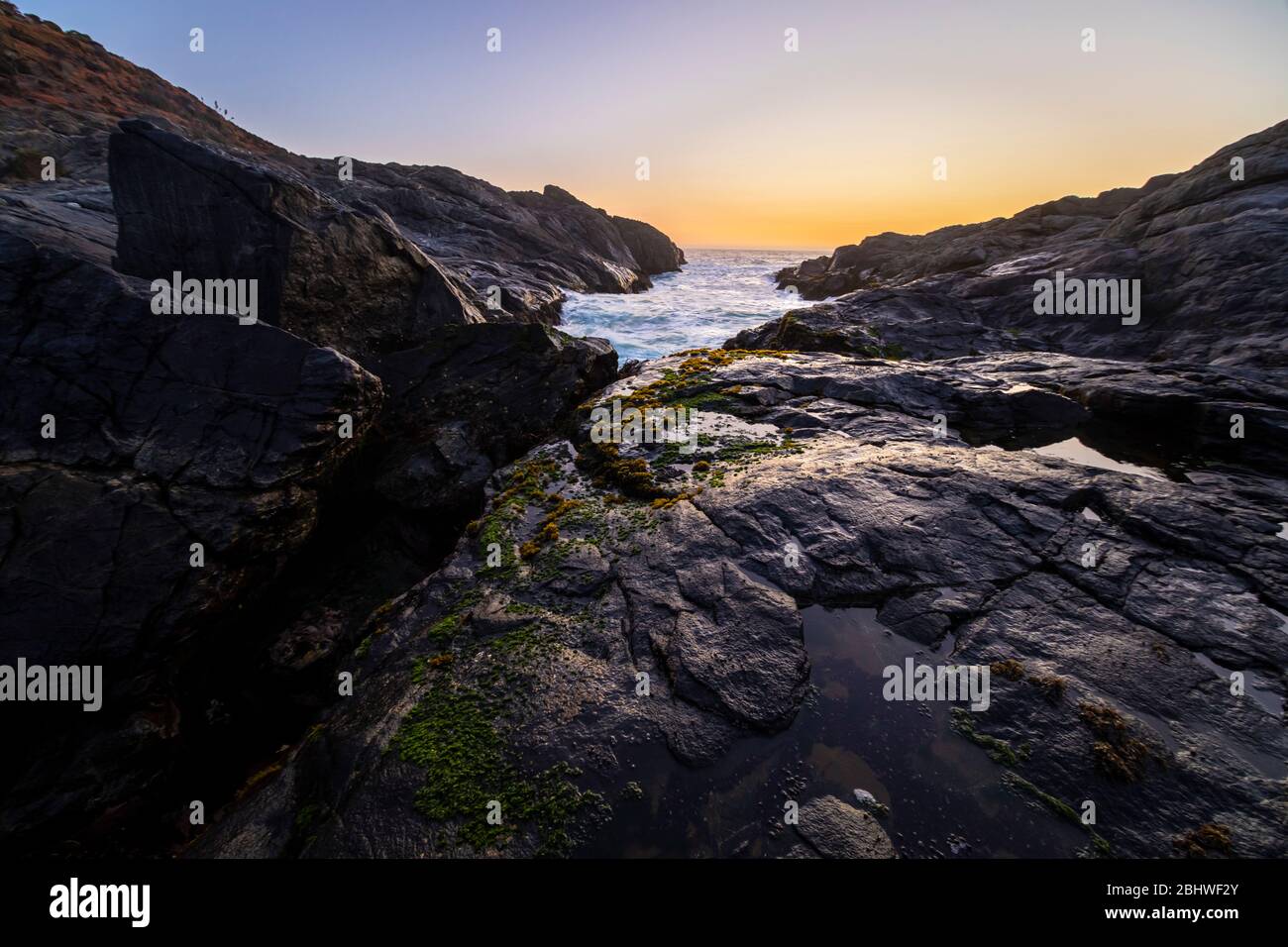 Une vue imprenable sur le coucher du soleil sur l'eau sur la côte chilienne. Un paysage idyllique de plage avec la lumière du soleil illuminant les rochers avec des tons orange Banque D'Images