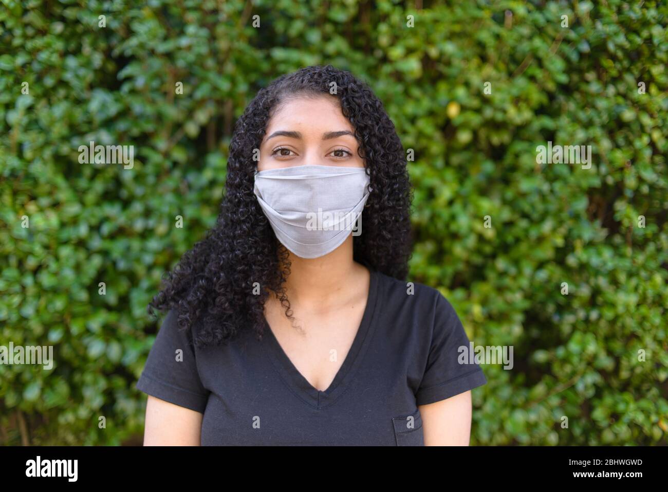 Femme noire sur fond urbain dans des vêtements décontractés portant un masque médical Banque D'Images