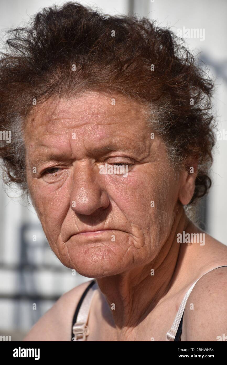 Le soleil brille sur le visage d'une femme plus âgée qui clignote ses yeux à la lumière vive Banque D'Images