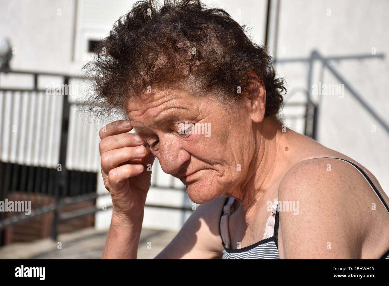 Le soleil brille sur le visage d'une femme plus âgée avec sa main levée sur son visage Banque D'Images