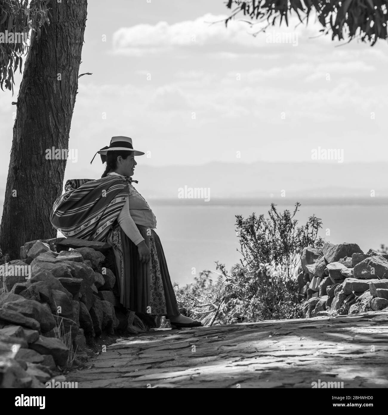 Photo en noir et blanc d'une femme indigène péruvienne quechua reposant contre un mur sur l'île Taquile, lac Titicaca, Pérou. Banque D'Images