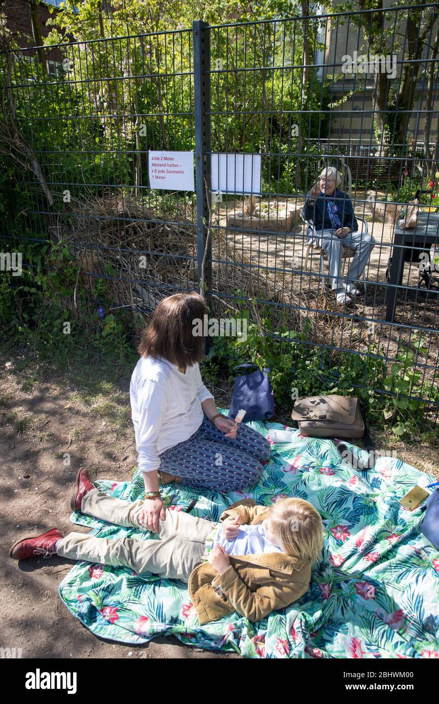24 avril 2020, Hambourg: Elsbeth Gregor (au dos), sa fille Katharina Gregor  et son petit-fils Jonathan sont assis à la clôture du jardin de la St.  Markus - Martha Stiftung centre de