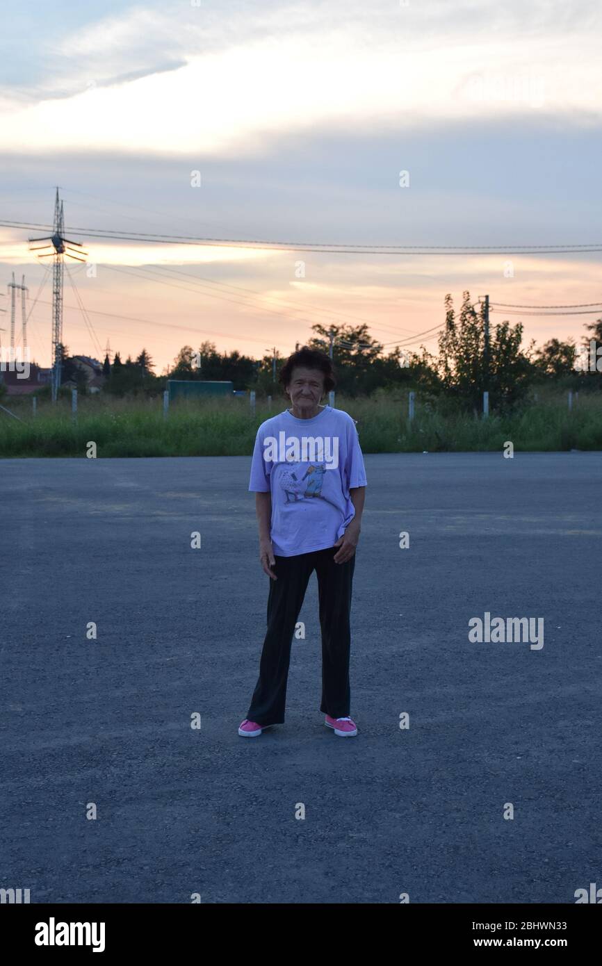 Une femme âgée en sneakers roses et une chemise de sport se tient en chemin. Banque D'Images