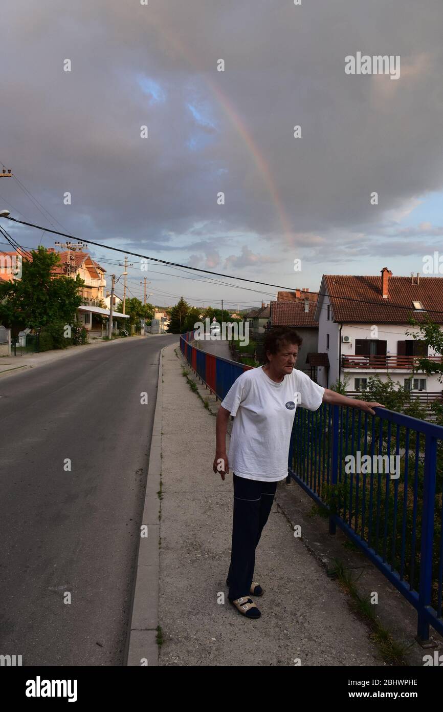Un paysage d'un petit pueblo. Une femme dans un chemisier blanc se tient à côté d'une clôture métallique sur le trottoir Banque D'Images