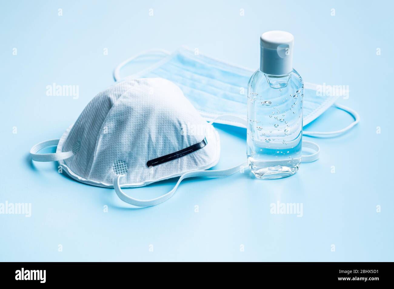 Gel désinfectant pour les mains et masque de protection contre le coronavirus sur fond bleu. Banque D'Images