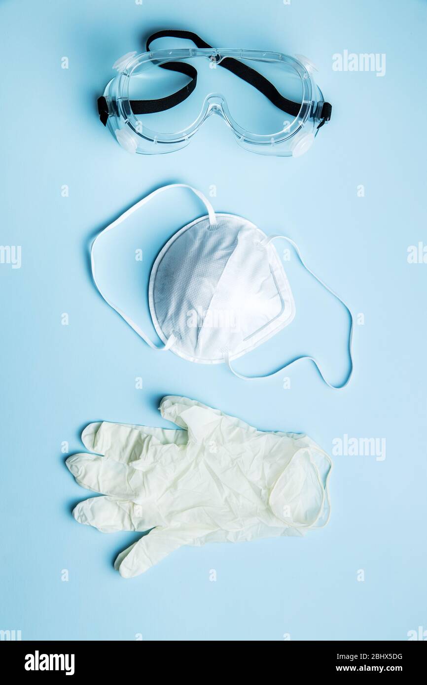 Lunettes, masque respiratoire et gants. Équipement de protection contre le coronavirus sur fond bleu. Vue de dessus. Banque D'Images