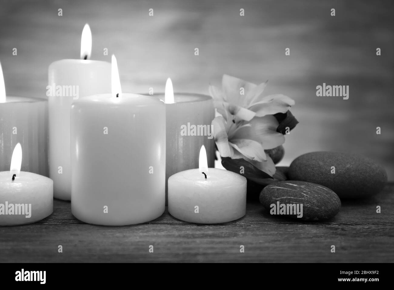 Belle composition avec bougies et pierres de spa sur table en noir et blanc Banque D'Images