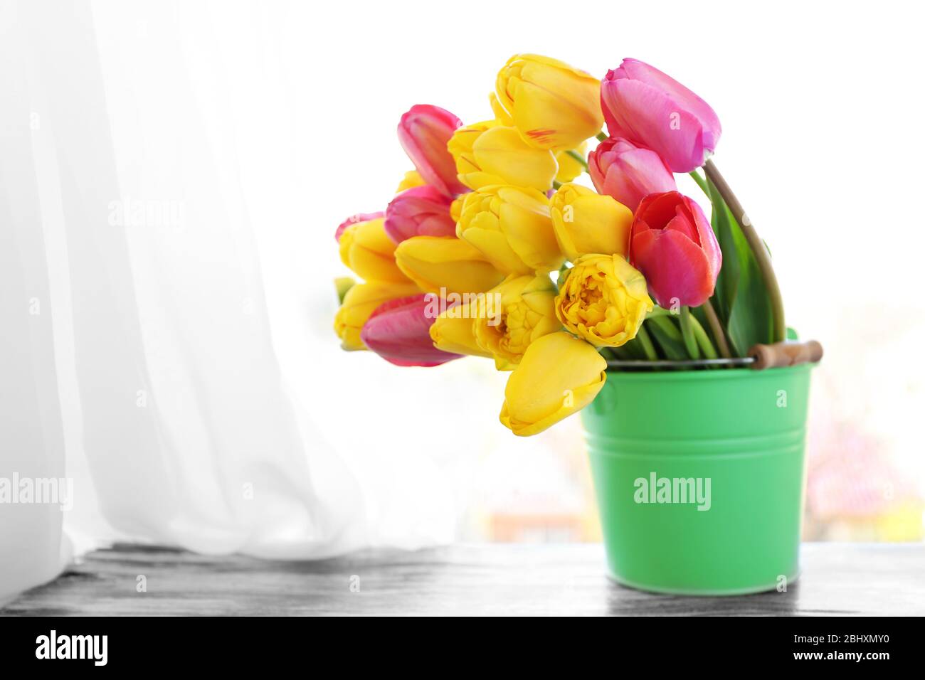 Beau bouquet de tulipes dans seau en métal sur le seuil de la fenêtre Banque D'Images