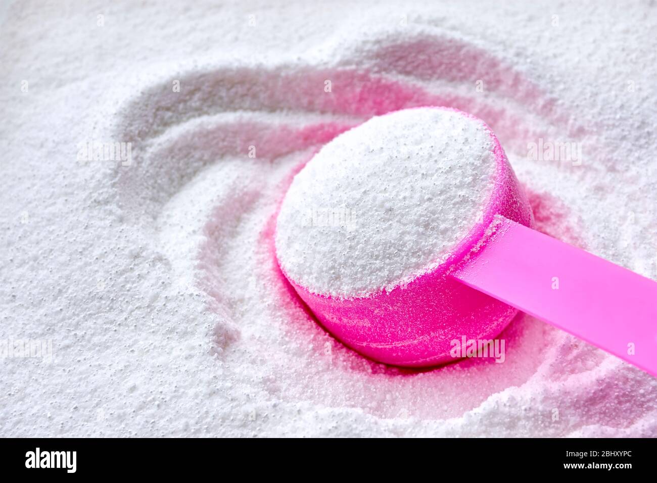 Lessive blanche en poudre pour machine à laver et pelle en plastique rose pour dosage. Image avec espace de copie. Banque D'Images