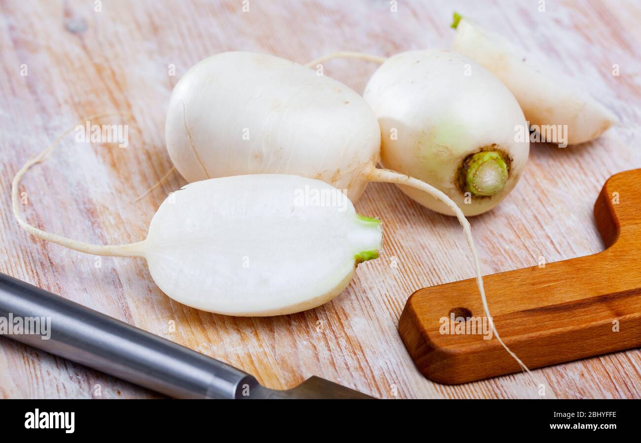 Navets blancs frais entiers et coupés en tranches sur une table en bois. Concept de cuisine végétarienne Banque D'Images