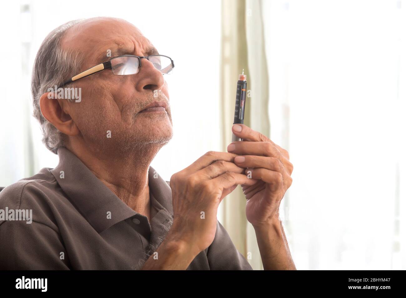 Homme senior tenant un stylo à insuline dans la main. (Santé et forme physique) Banque D'Images