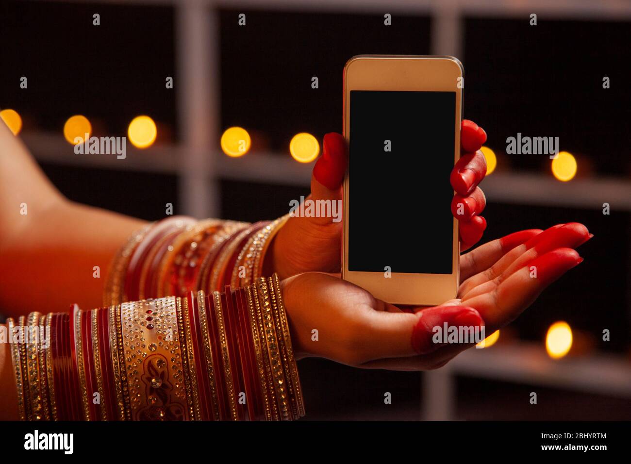 Jeune femme tenant un téléphone portable entre ses mains à l'occasion de Diwali. Banque D'Images