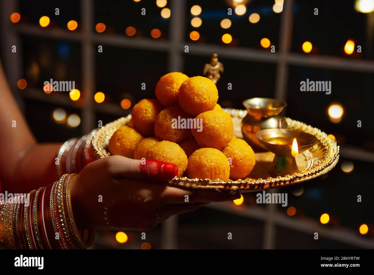 Jeune femme tenant un plateau de bonbons dans ses mains à l'occasion de Diwali. Banque D'Images