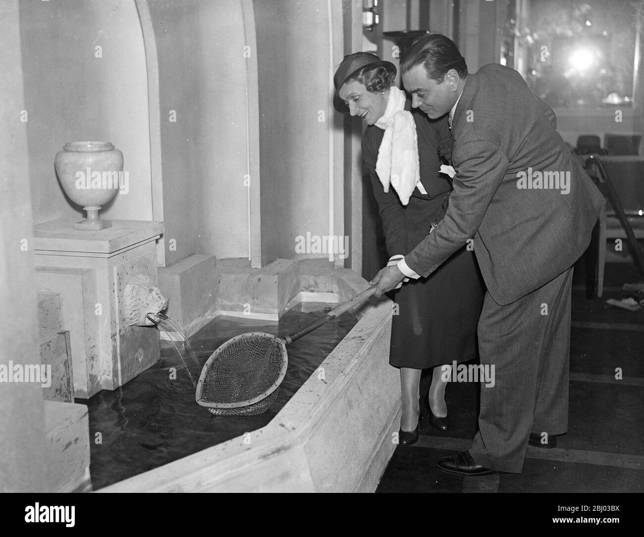 Ciros Club ouvre de nouveau avec un étang de pêche pour les clients de prendre leur propre poisson et de le voir préparé pour table . - Ciros Club , le restaurant de Londres bien connu , a été rouvert après de longues modifications au bâtiment . L'une de ses nouvelles caractéristiques est un étang de pêche dans lequel les clients peuvent attraper leur propre truite , voir il tué et préparé par le chef pour la table . - un client au restaurant Ciros Club récemment ouvert , pêche à la truite de la piscine pour être préparé pour un repas . - 2 mai 1932 Banque D'Images