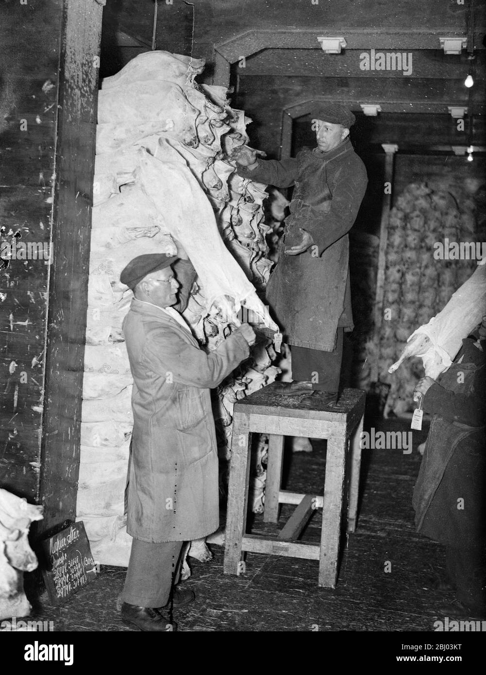 Londoner qui porte toujours des chapeaux et des manteaux ! . Ils fonctionnent dans le stockage à froid . - même dans ce brûlant août il y a un endroit à Londres où les chapeaux et les manteaux sont toujours les bienvenus . - c'est le froid stockage de l'Administration du Port de Londres dans Charterhouse Street , où les hommes manipulent la viande toute la journée avec des vêtements lourds comme protection contre la frsot . - 8 août 1935 Banque D'Images