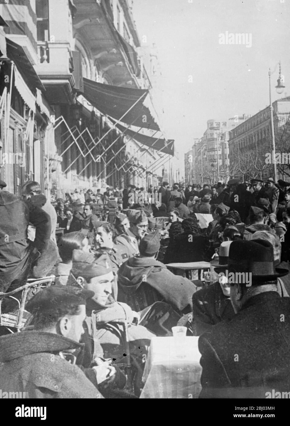 La guerre - mais la vie continue. - malgré l'évolution de la situation de guerre, Burgos, siège du gouvernement provisoire des rebelles espagnols, est une ville gay. Non seulement c'est le centre animé de l'administration du général Franco, mais c'est aussi un lieu de vacances pour les soldats insurgés en congé du front de bataille. - spectacles photo: Les soldats discutant des dernières nouvelles du front dans l'un des cafés en plein air sur les trottoirs bondés de Burgos. - 7 avril 1937 Banque D'Images