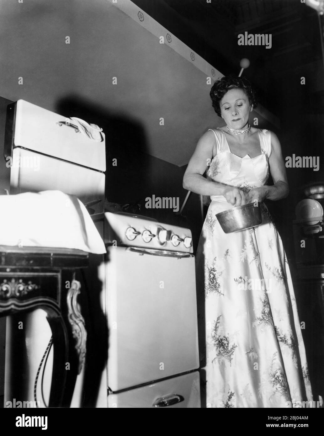 Mme Phyllis Cradock, la moitié féminine de l'équipe bon viveur, prépare ses trois plats dans le duel culinaire avec le restaurateur de Paris M. Raymond Oliver au café Royal. Le duel a eu lieu après que M. Oliver a dit que les femmes ne pouvaient pas créer de nouveaux plats. Mme Cradock l'a défié - et ils ont tous deux créé trois nouveaux plats à juger par trois experts en cuisine. Mme Cradock a fait sa cuisine dans une boule. - 9 janvier 1956 Banque D'Images