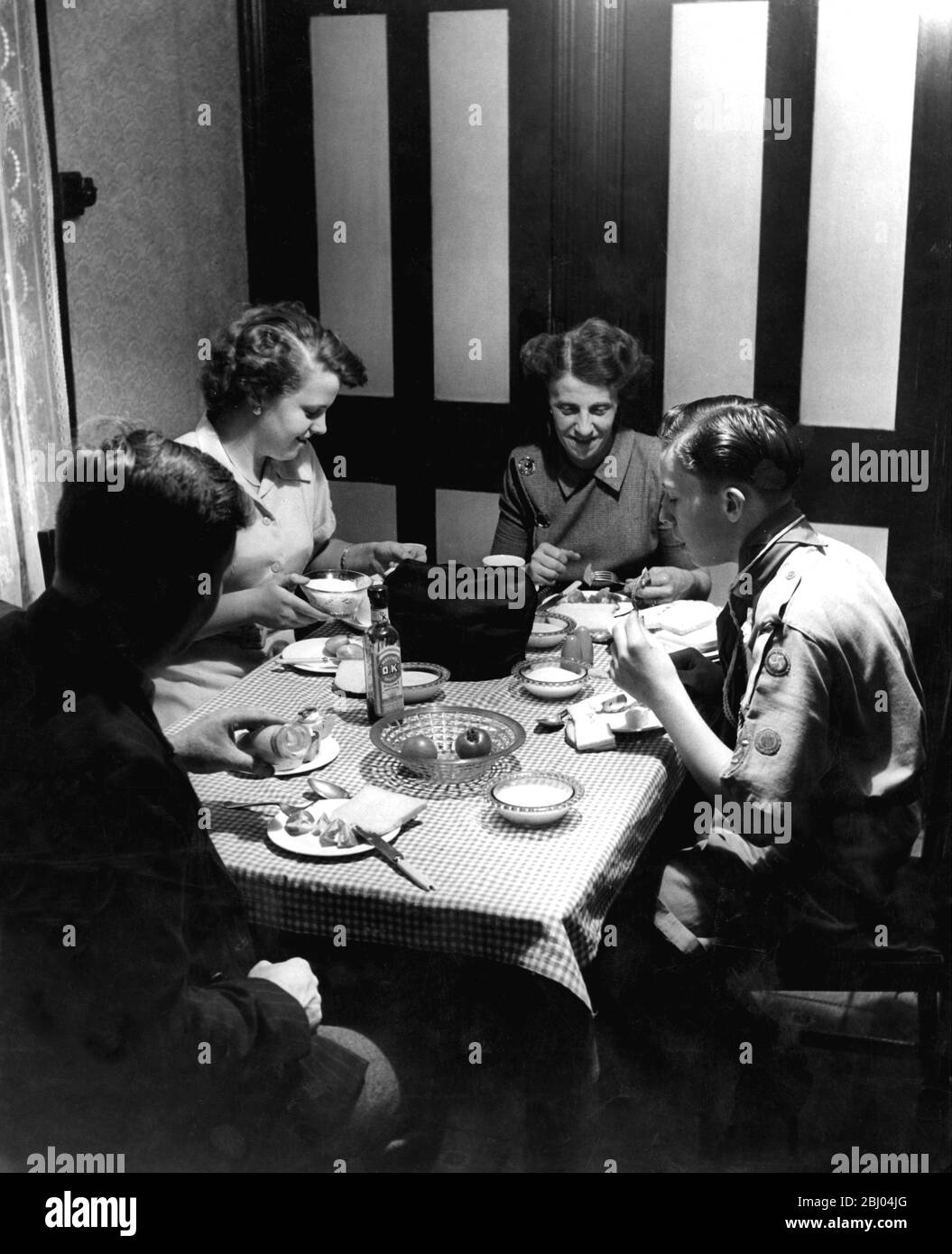 Une famille de quatre personnes ayant repas du soir avec pain, fromage et tomates . 1952 - George Tyler et sa femme Doris avec leurs deux enfants Joan et Brian Banque D'Images
