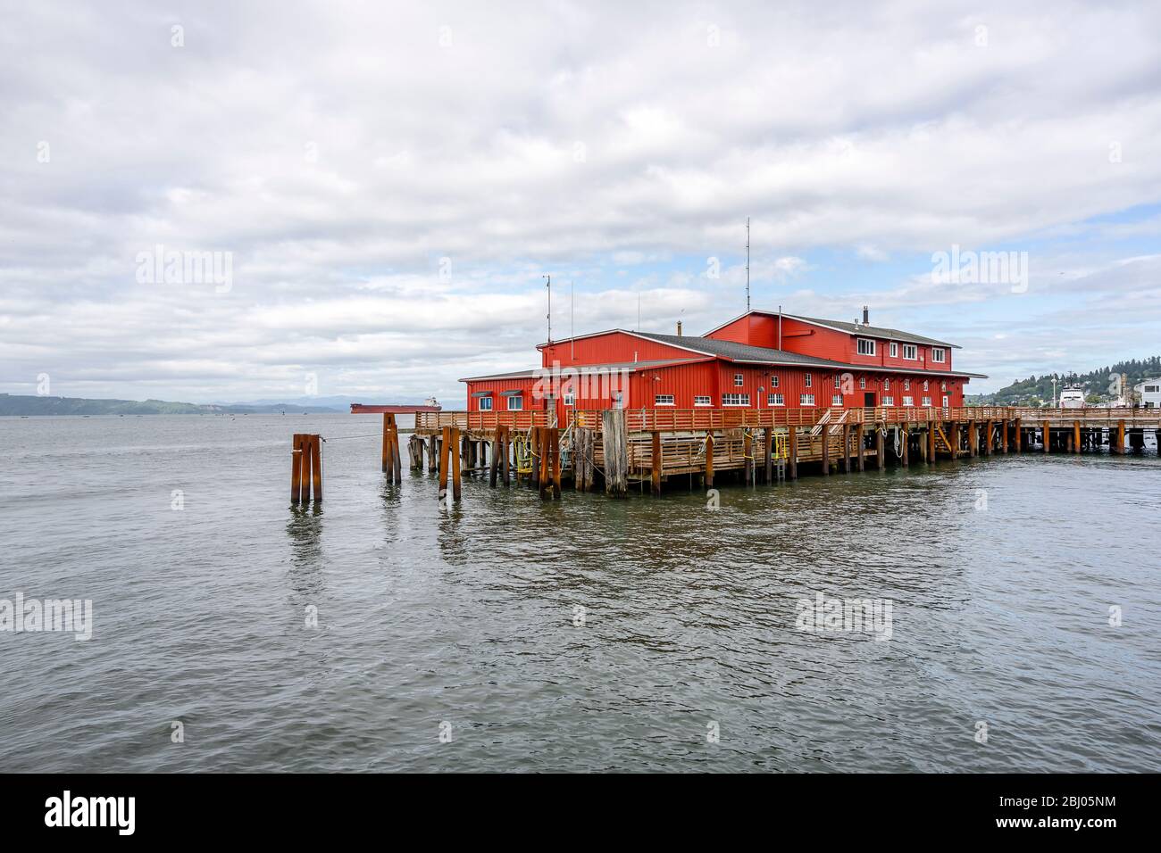 Bâtiment en bois rouge sur l'ancien quai de pêche avec des piles de bois qui dépasse de l'eau à l'échelle de l'embouchure de la rivière Columbia, dans le Pacifique sur la ville Astoria Banque D'Images