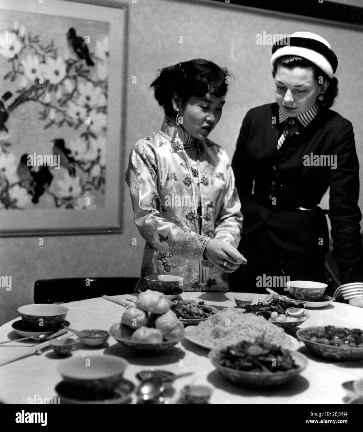 Mme Hsu donne quelques conseils chinois à une mariée. - Mme P y Hsu propriétaire du nouveau restaurant chinois de Londres montre l'écrivain illustré Anne Alexeiev comment cuisiner et manger la nourriture de la manière chinoise. Mme Hsu et son équipe de jeunes filles chinoises feront la démonstration à la Foire alimentaire britannique. - la nourriture est prévue sur la table du dîner - 11 septembre 1954 Banque D'Images