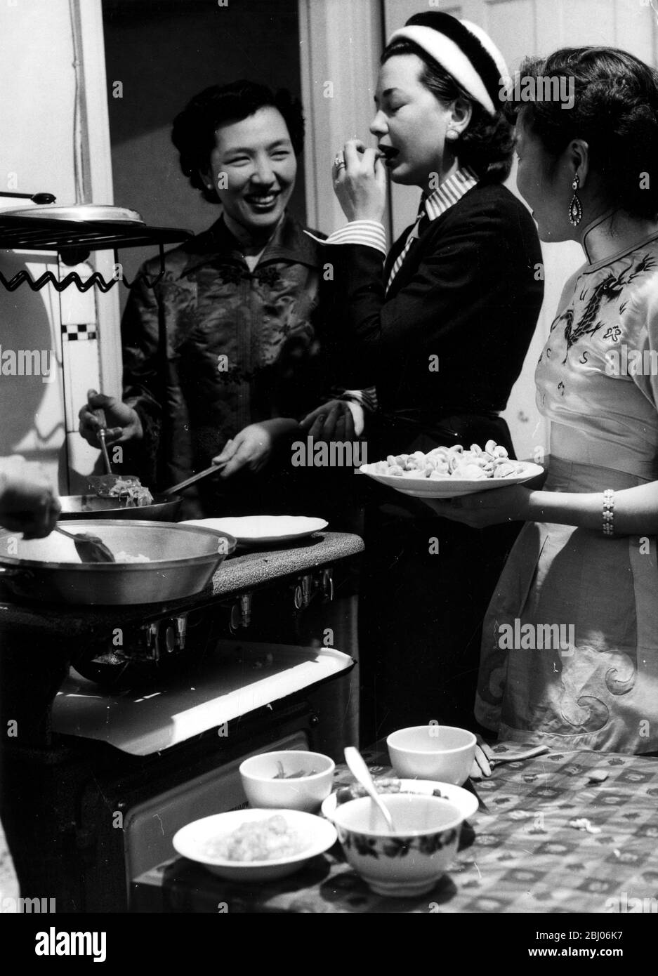 Mme Hsu donne quelques conseils chinois à une mariée. - Mme P y Hsu propriétaire du nouveau restaurant chinois de Londres montre l'écrivain illustré Anne Alexeiev comment cuisiner et manger la nourriture de la manière chinoise. Mme Hsu et son équipe de jeunes filles chinoises feront la démonstration à la Foire alimentaire britannique. - la nourriture est prévue sur la table du dîner - 11 septembre 1954 Banque D'Images
