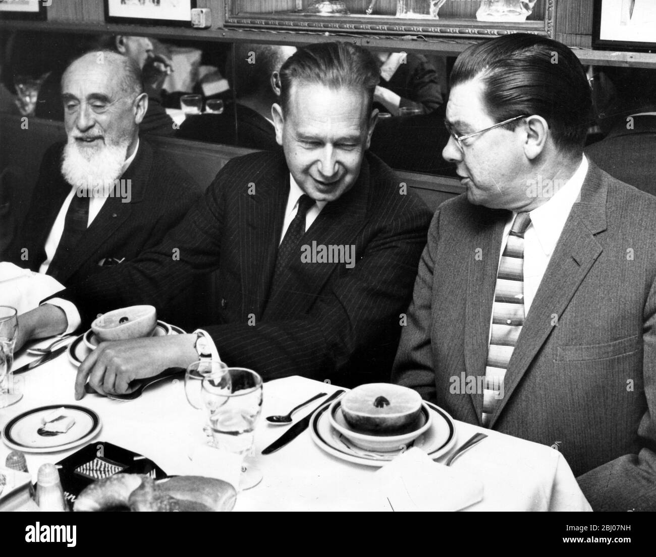 Le Secrétaire général des Nations Unies, Dah Hammarskjold (centre), discute avec le correspondant de la presse des Nations Unies, Bruce Munn (à droite), lors du déjeuner au restaurant Danny's Hideaway. L'homme barbu sur la gauche est Arnold Van Dias. - 9 avril 1958 Banque D'Images