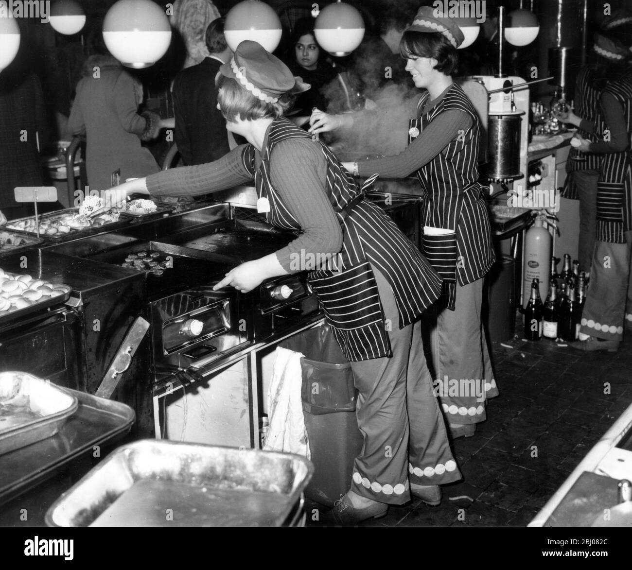 Un changement générationnel à mesure que les nippies deviennent des Chippies dans ce nouveau restaurant de restauration rapide de Londres appelé 'Chips with Everything' après le jeu Arnold Wesker du même nom. On peut voir Denise French et Beverley Plum qui servent des repas à la Mod Generation avec des repas moins de quatre shillings et six penny. - Chancellerie Lane, Londres, Angleterre - 24 novembre 1965 Banque D'Images