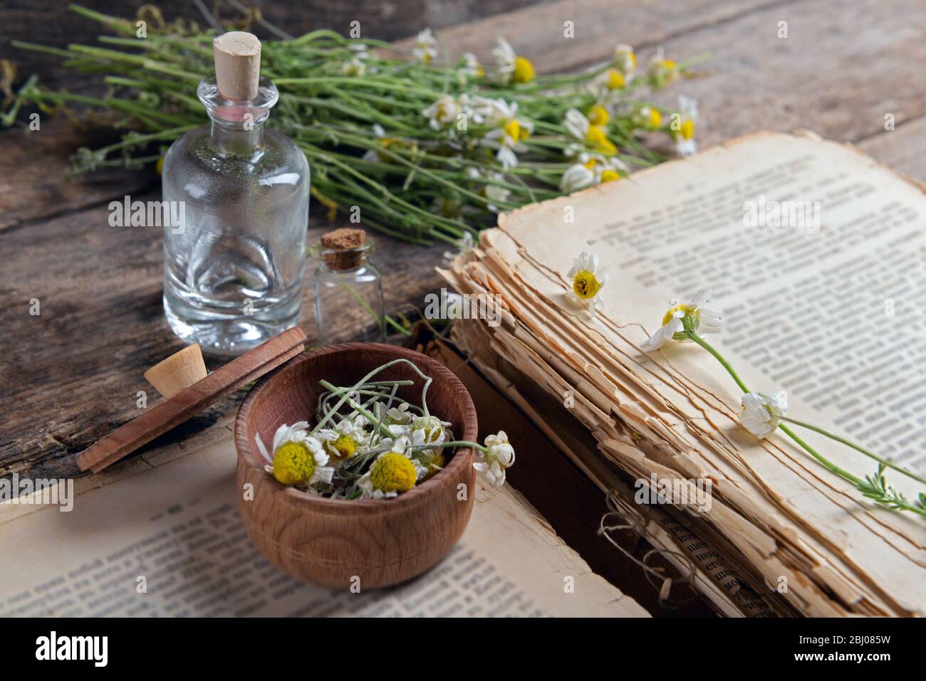 Vieux livre avec fleurs sèches dans mortier sur table près Banque D'Images