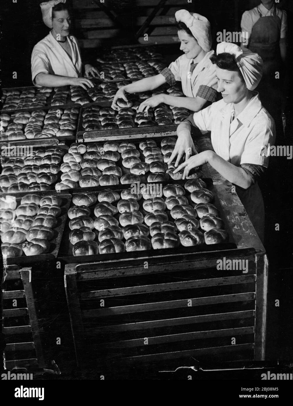 Des jeunes filles dans les boulangeries de Cadby Hall de J Lyons et co, se préparent à envoyer une partie de l'énorme nombre de petits pains chauds de croix cuits le bon vendredi. En cette année de rationnement de pain, ils sont des petits pains de croix chauds pour la première fois. - 3 avril 1947 Banque D'Images