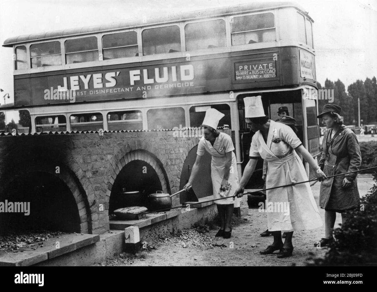 Fours de cuisine extérieurs habités par des femmes et surveillés par - une femme chauffeur de bus et de conductrices. Banque D'Images