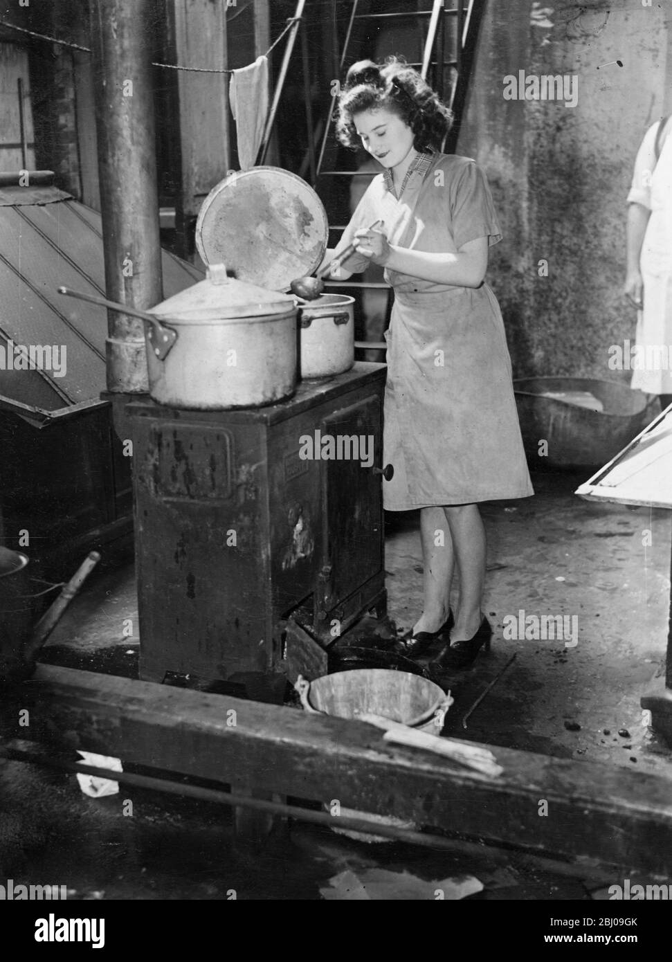 Battre la grève du gaz. - les ingénieurs de J Lyons et de la Compagnie londonienne ont travaillé toute la nuit sur des arrangements de cuisson d'urgence pour lutter contre la pénurie de gaz causée par la grève non officielle de 2000 ingénieurs d'entretien de la Gas Light and Coke Company. Chaque méthode de chauffage disponible est utilisée, y compris les poêles à huile, les cuisines de campagne et les feux ouverts. La quantité normale de pain, de gâteaux et de nourriture a été cuite aujourd'hui (lundi) mais dans certains cas Lyon peut être obligé de servir des repas de la variété de 'blitz' de temps de guerre. - des spectacles photo, la cuisine sur un feu ouvert dans un café Lyons dans la ville de Londres, aujourd'hui, Banque D'Images