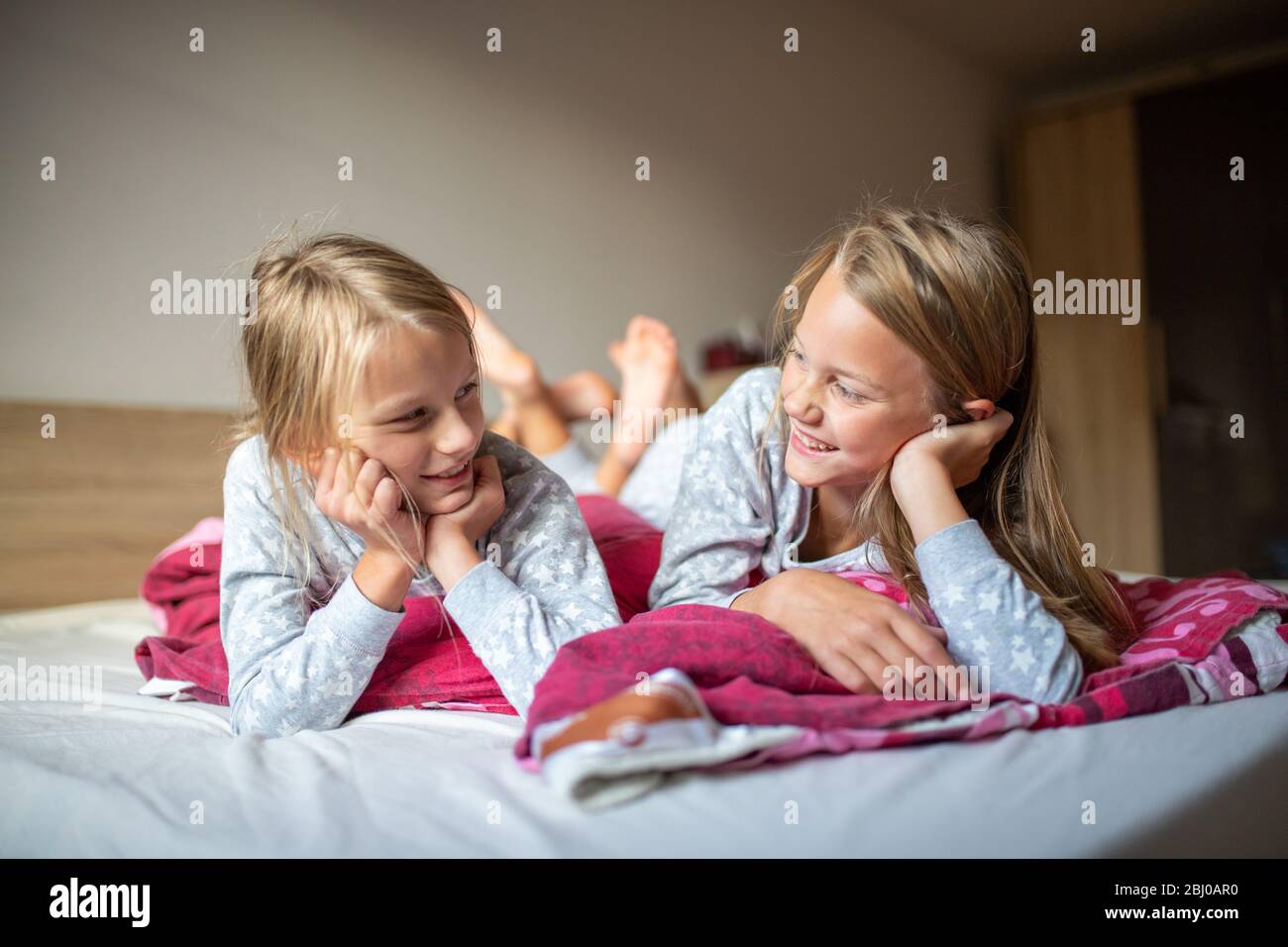 Deux filles se coutant sur le lit et souriant l'une à l'autre Banque D'Images