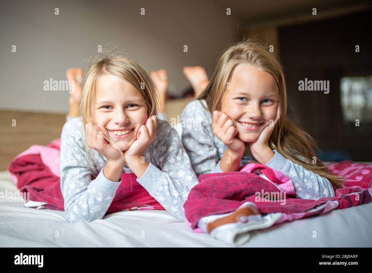 Deux filles allongé sur le lit et souriant dans l'appareil photo Banque D'Images