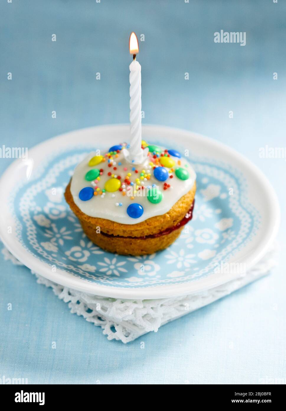 Muffin décoré comme un premier gâteau d'anniversaire avec icin gand bougie simple brûlant - Banque D'Images