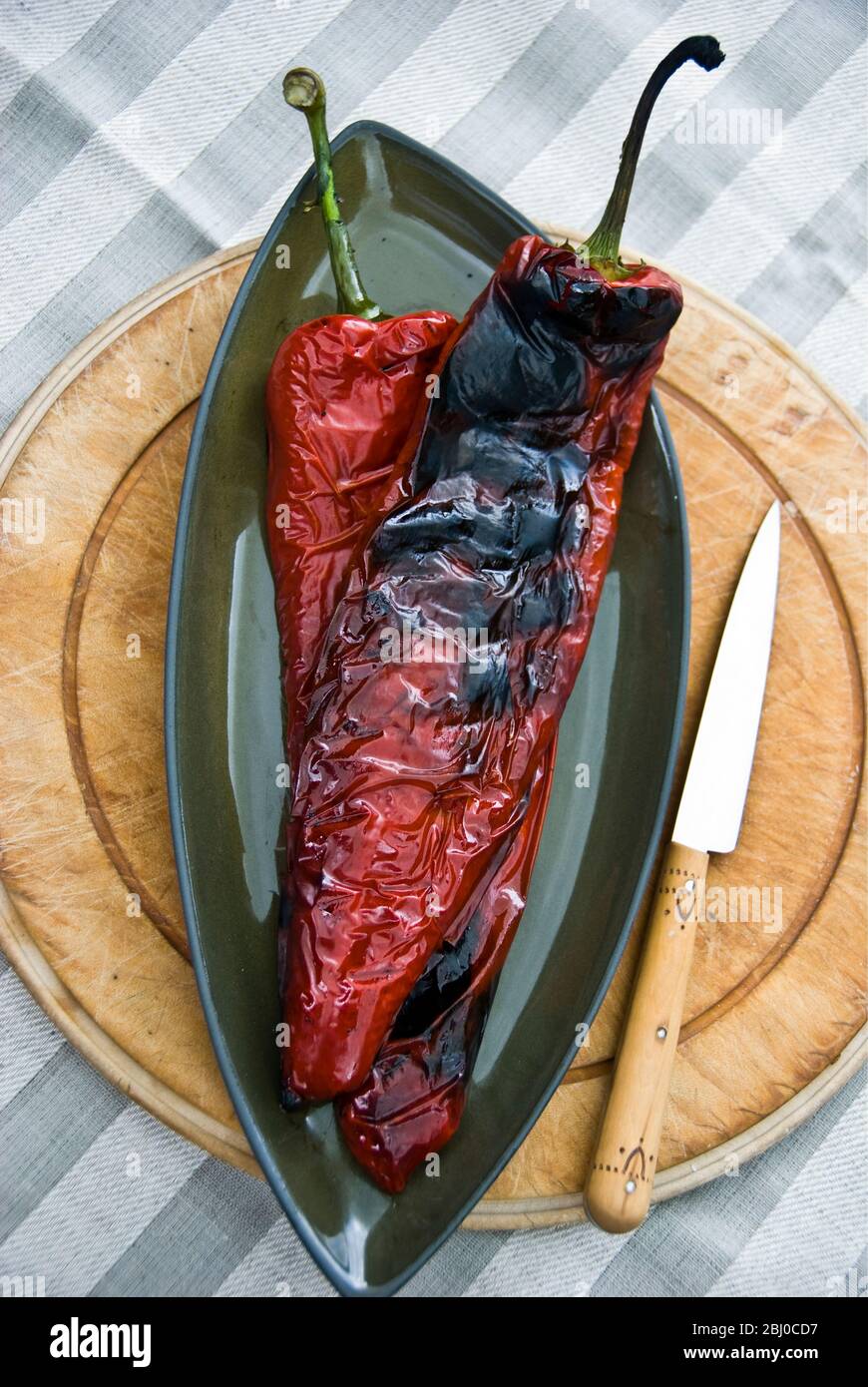 Poivrons rouges longs grillés sur barbecue montrant la peau grillée - Banque D'Images