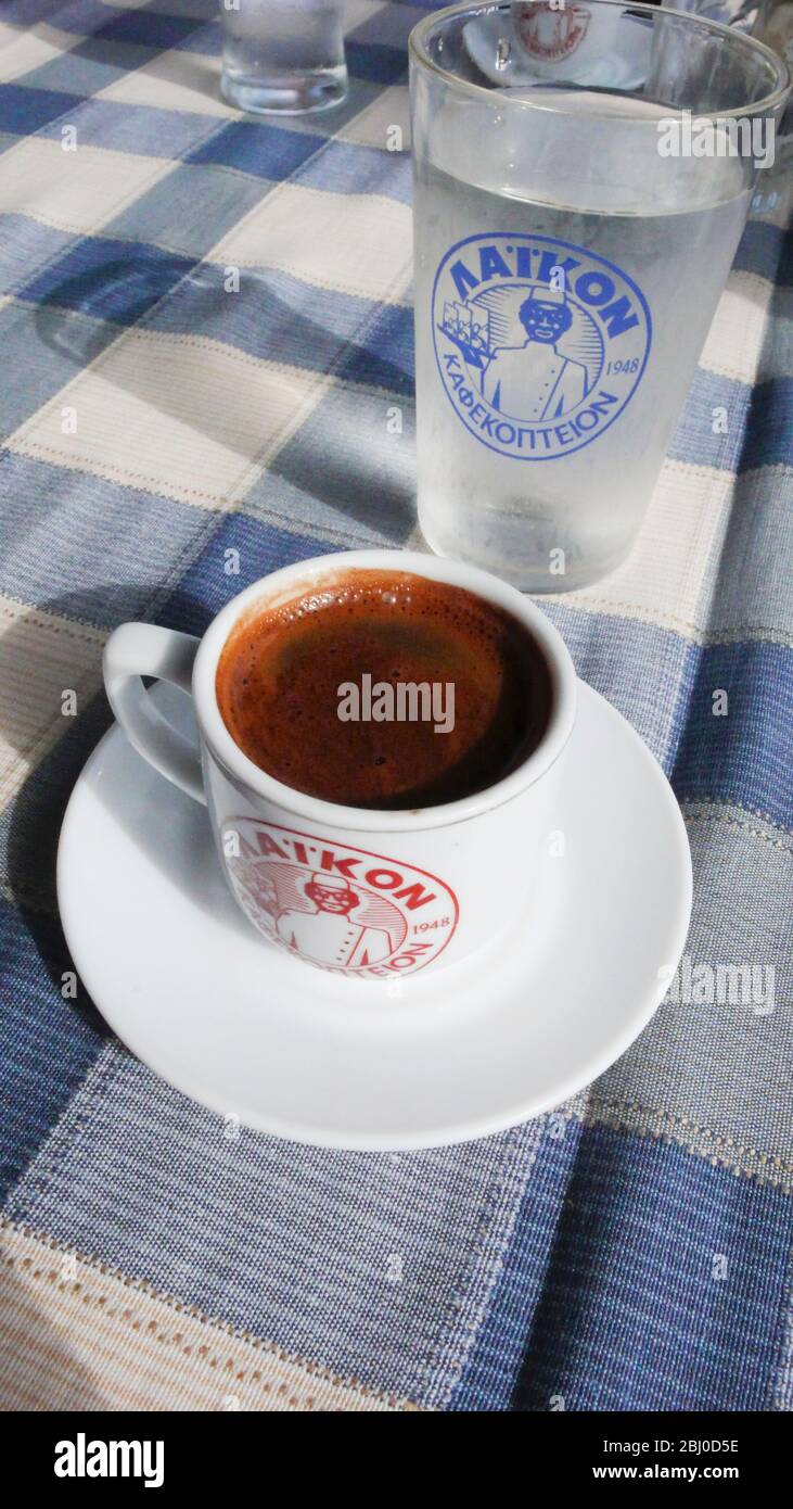 Petite tasse de café grec fort, avec un verre d'eau sur la table du restaurant de plage dans le sud de Chypre - Banque D'Images